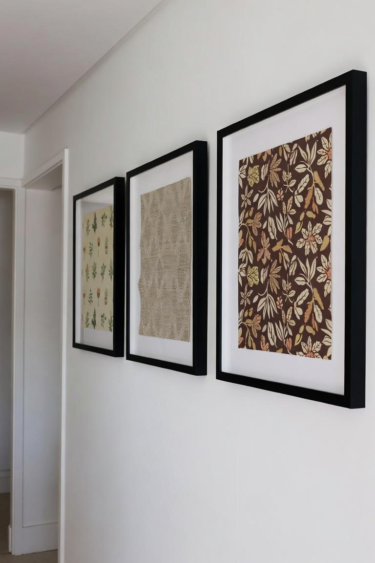 three framed wallpaper and fabric samples as wall art in hallway black frames botanical and geometric patterns