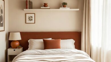 small bedroom with terracotta upholstered headboard, floating shelves, and storage ottoman