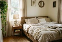 aesthetic bedroom with layered neutral linen bedding, ceramic lamp and morning light