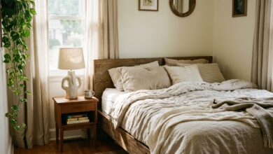 aesthetic bedroom with layered neutral linen bedding, ceramic lamp and morning light