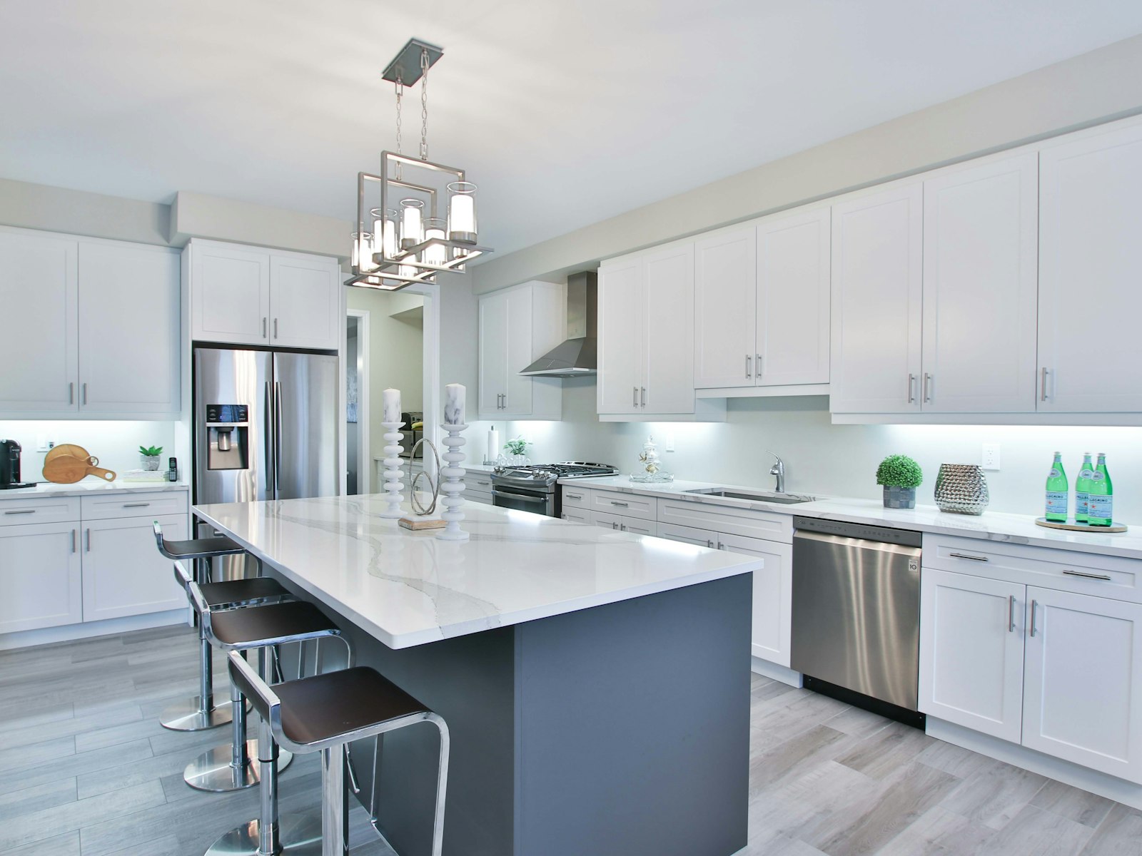 A modern kitchen with white cabinets, a dark island, and stainless steel appliances