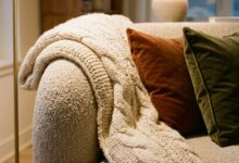 Chunky knit throw draped over the arm of a neutral sofa in an autumn living room