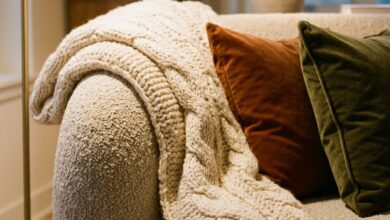 Chunky knit throw draped over the arm of a neutral sofa in an autumn living room