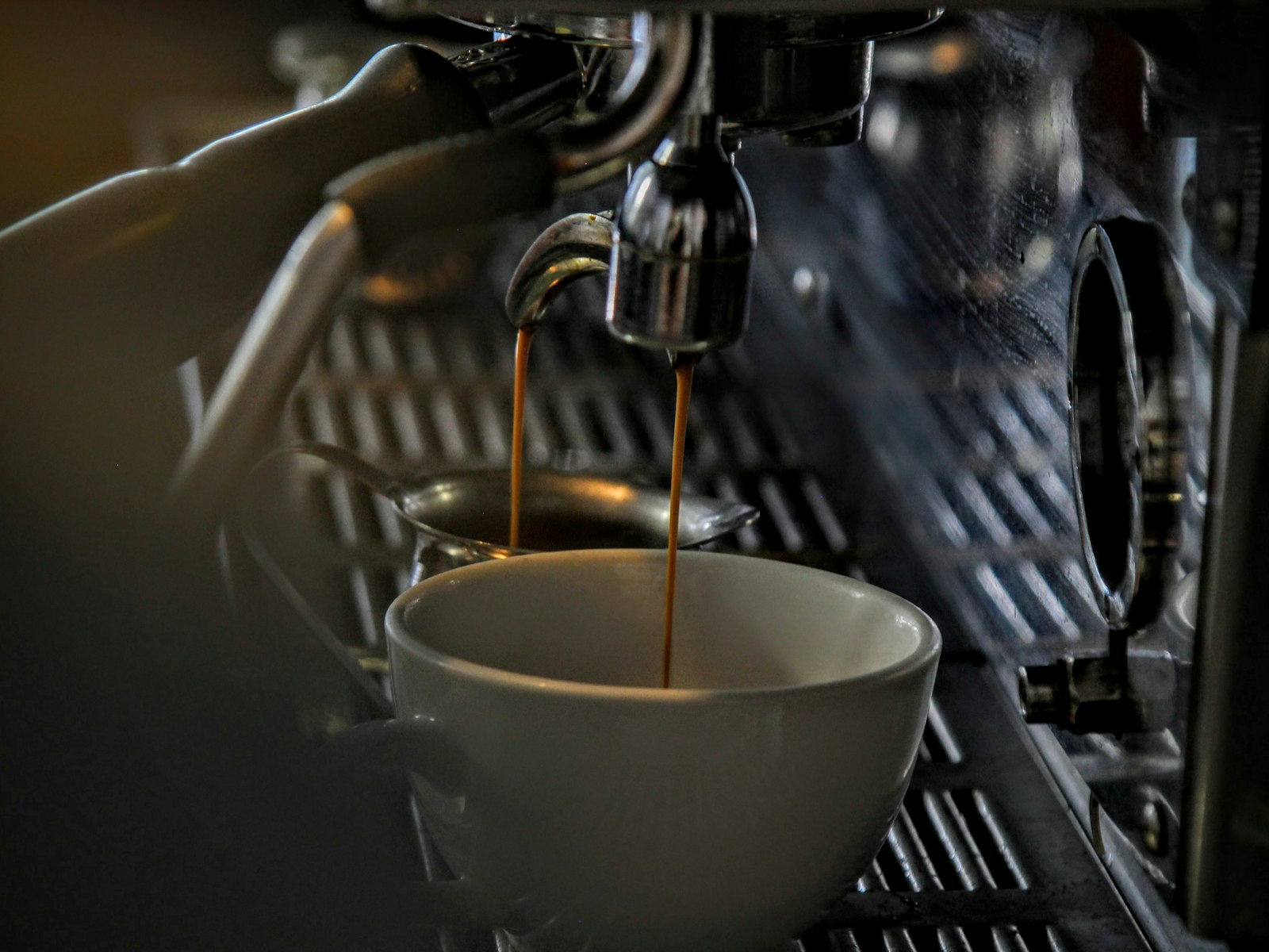 Espresso dripping into a porcelain mug from a steel machine
