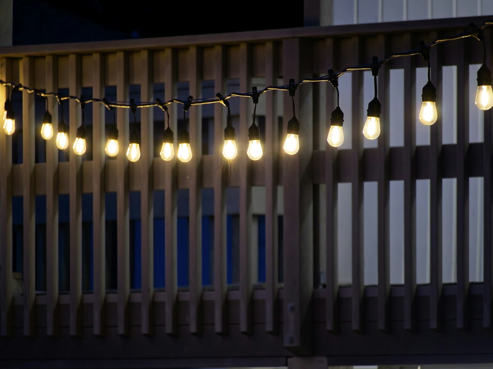 String lights illuminate a wooden deck railing at night