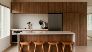 A modern kitchen with walnut cabinetry, a white island, and four wood stools