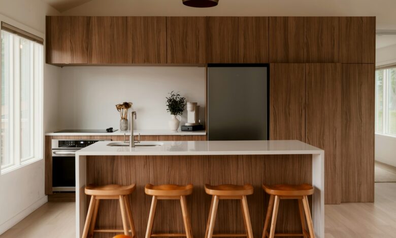 A modern kitchen with walnut cabinetry, a white island, and four wood stools
