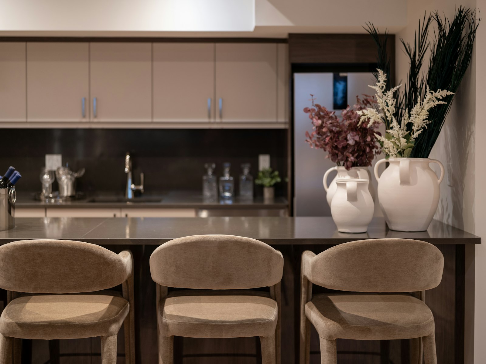 A modern kitchen with bar stools and decorative vases
