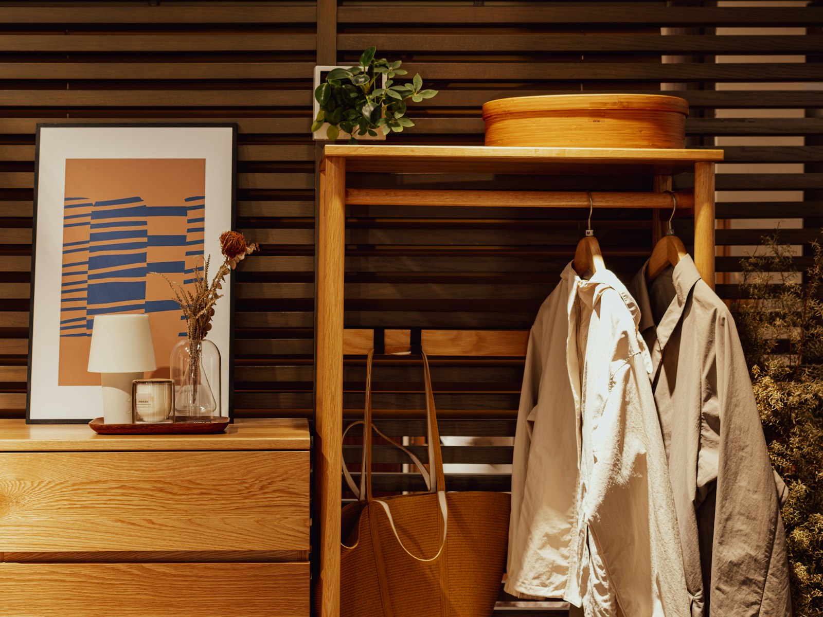 Wooden dresser with artwork and hanging coats