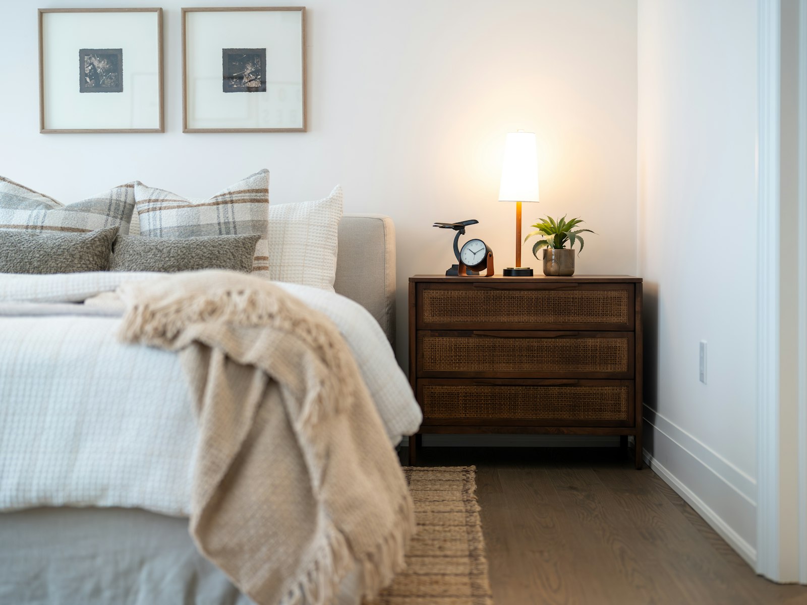 Bed with a faux fur throw, grey pillows and a glowing bedside lamp