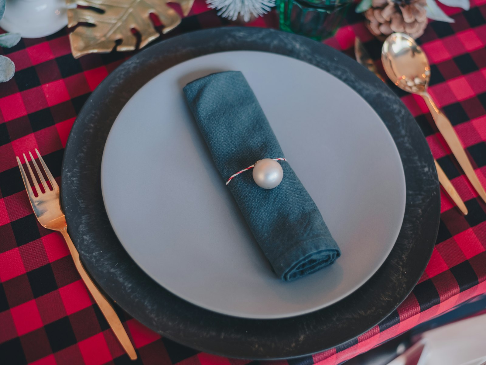 Buffalo plaid Christmas place setting with a charger, teal napkin and gold flatware