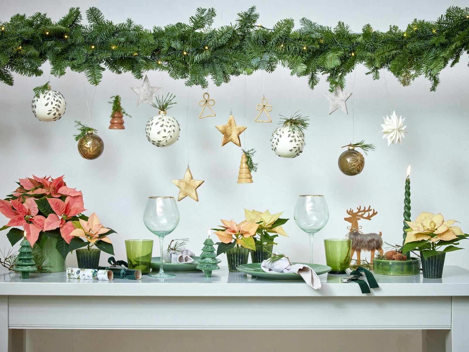 White console with a garland, hanging ornaments and poinsettias