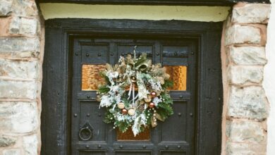 Dark front door with a natural Christmas wreath framed by a stone entryway