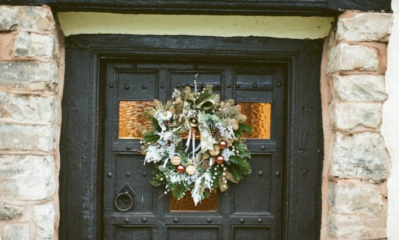 Dark front door with a natural Christmas wreath framed by a stone entryway