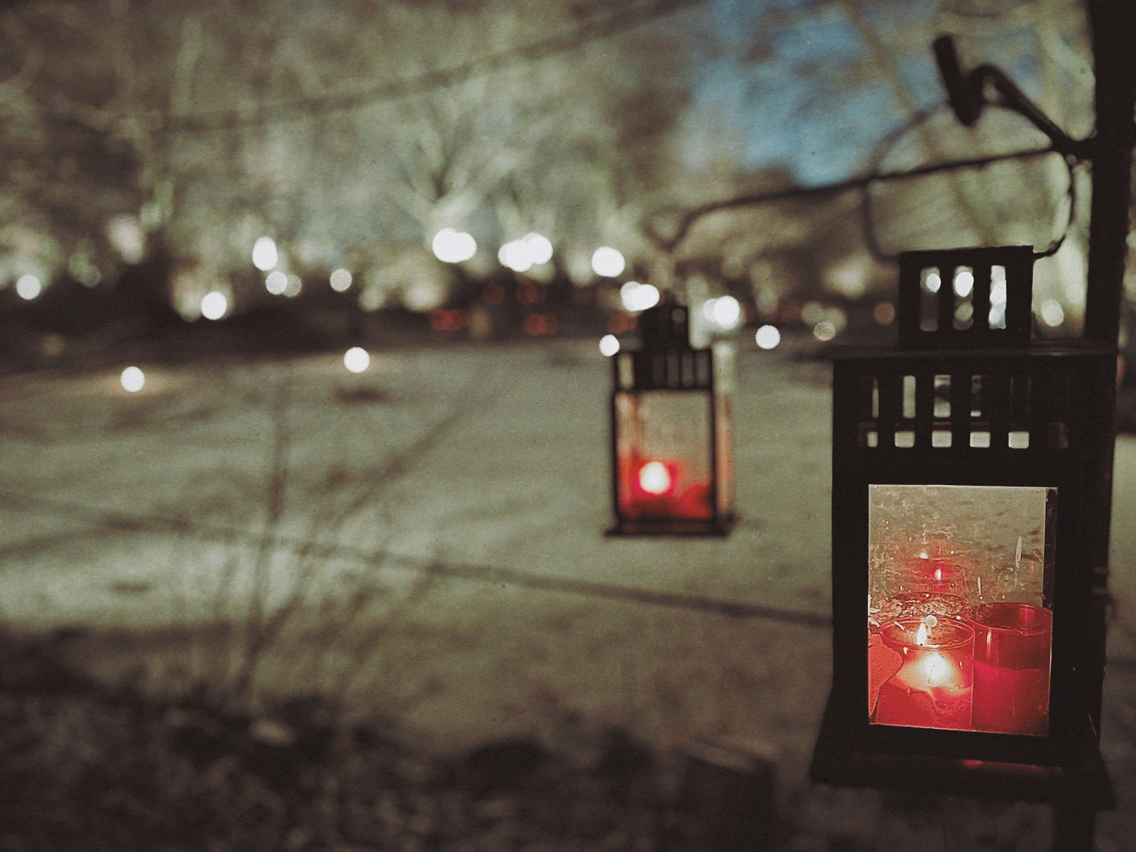 Black lanterns with candles glowing outdoors at dusk