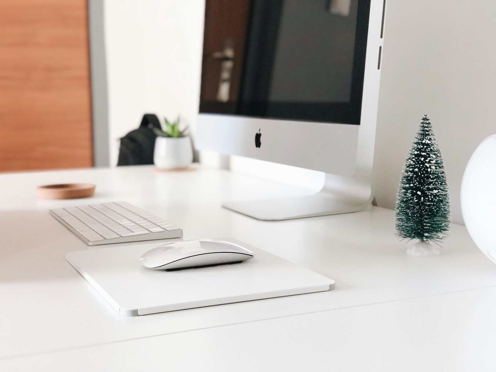 Turned-off Apple monitor beside apple keyboard and mouse – Christmas office decor idea