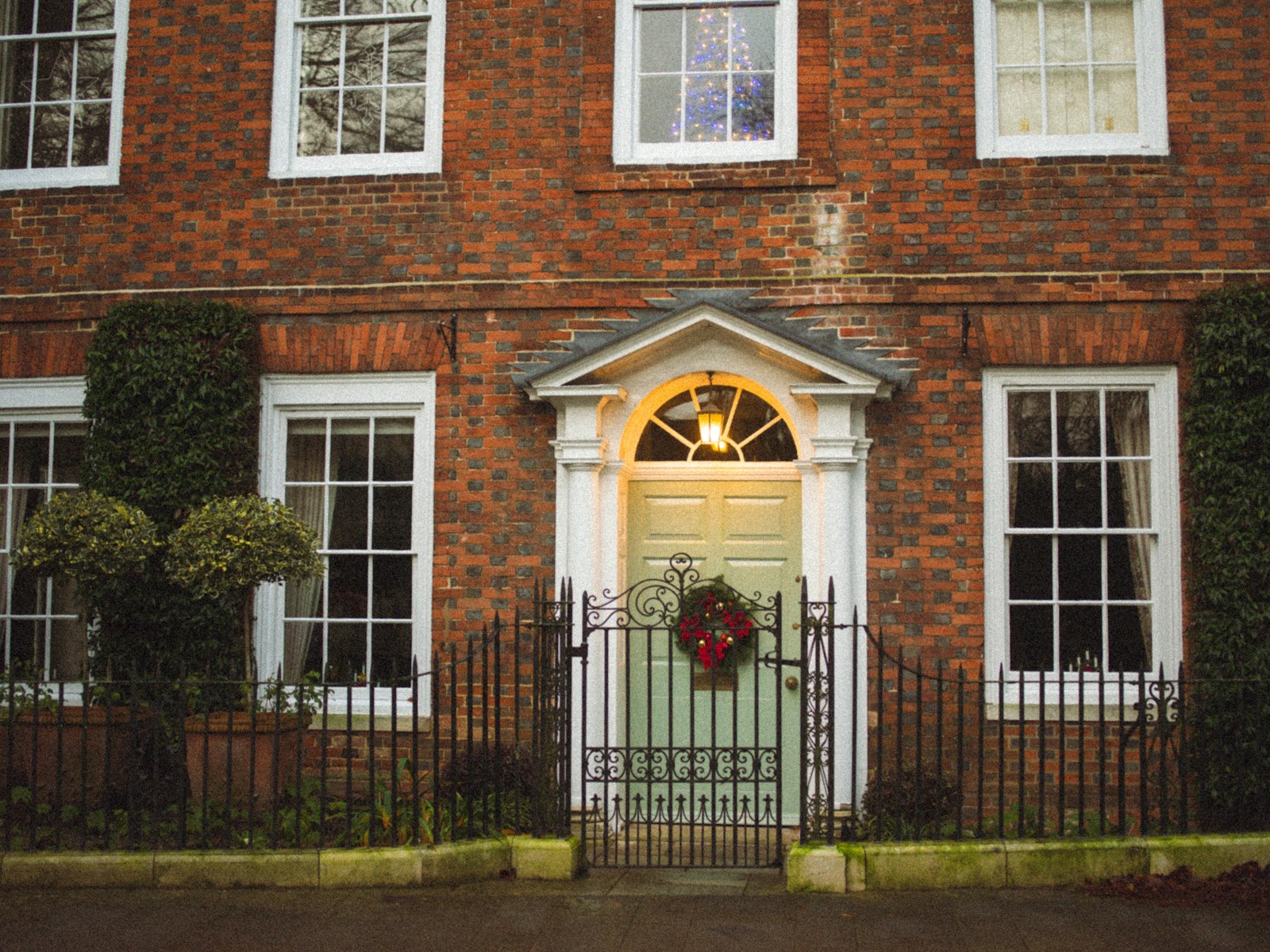 A red brick house with a green door and wreath – Christmas outdoor decor idea