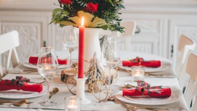 Christmas tablescape with red napkins, a red taper candle and a winter floral centerpiece on a white table