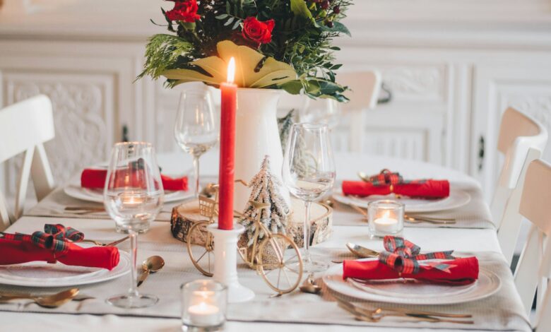 Christmas tablescape with red napkins, a red taper candle and a winter floral centerpiece on a white table