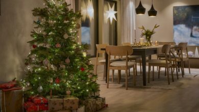 Decorated Christmas tree with warm lights and wrapped gifts in an open living and dining room
