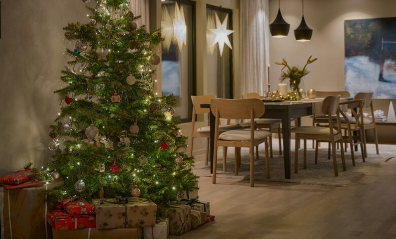 Decorated Christmas tree with warm lights and wrapped gifts in an open living and dining room