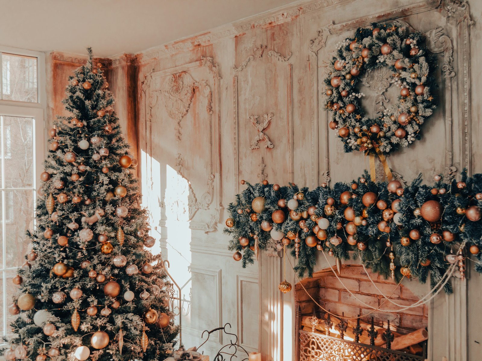 Lush Christmas mantel garland loaded with copper ornaments under a matching wreath beside a decorated tree
