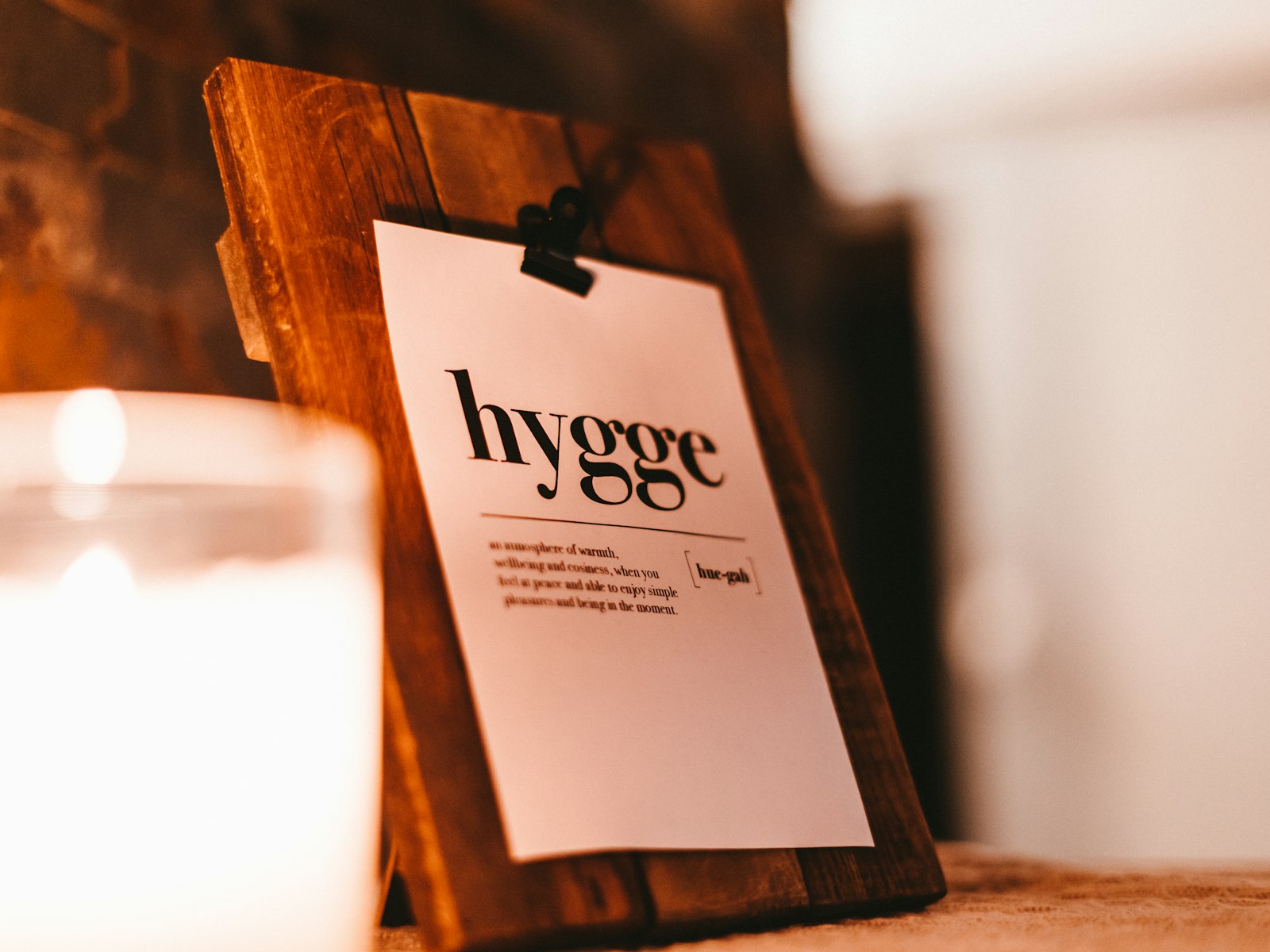 Candle next to a card that defines hygge