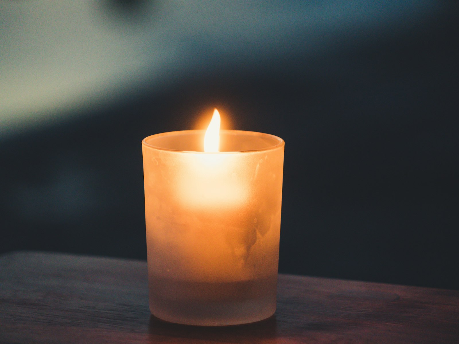 Single candle glowing in a frosted glass holder