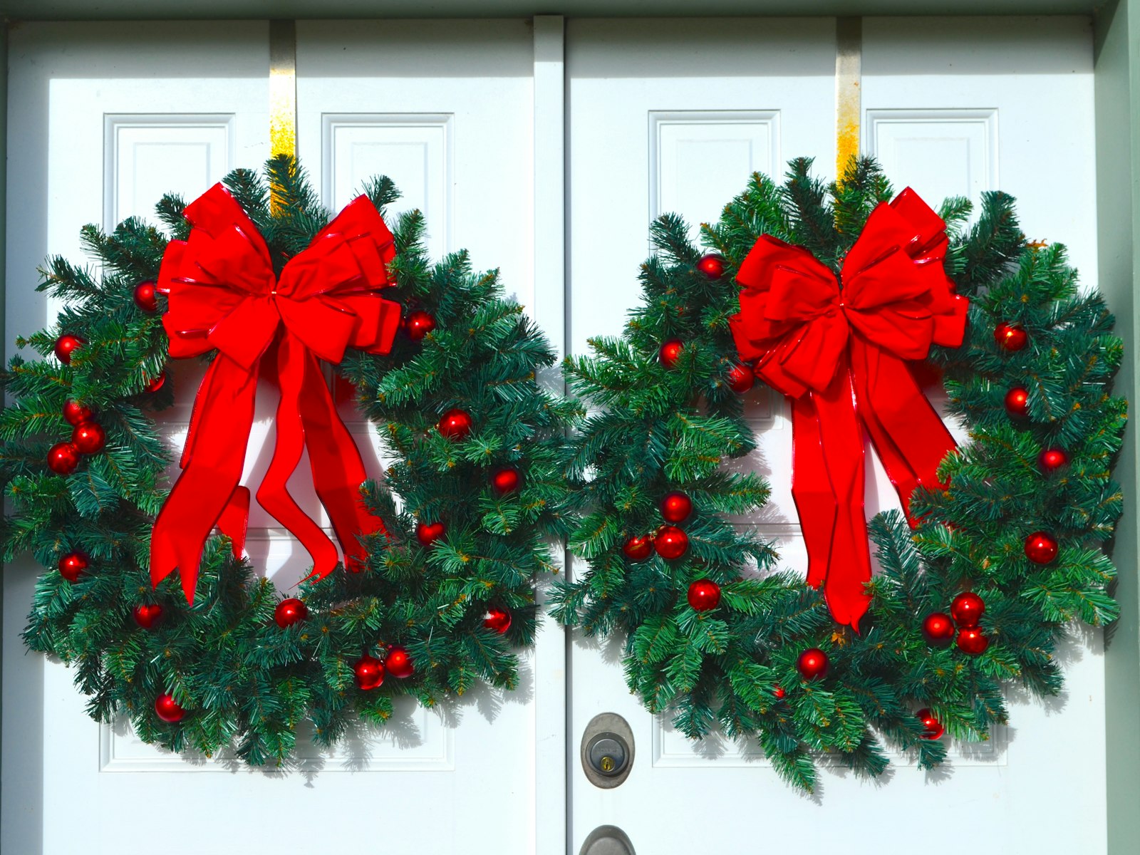 Matching wreaths with red bows on white double doors