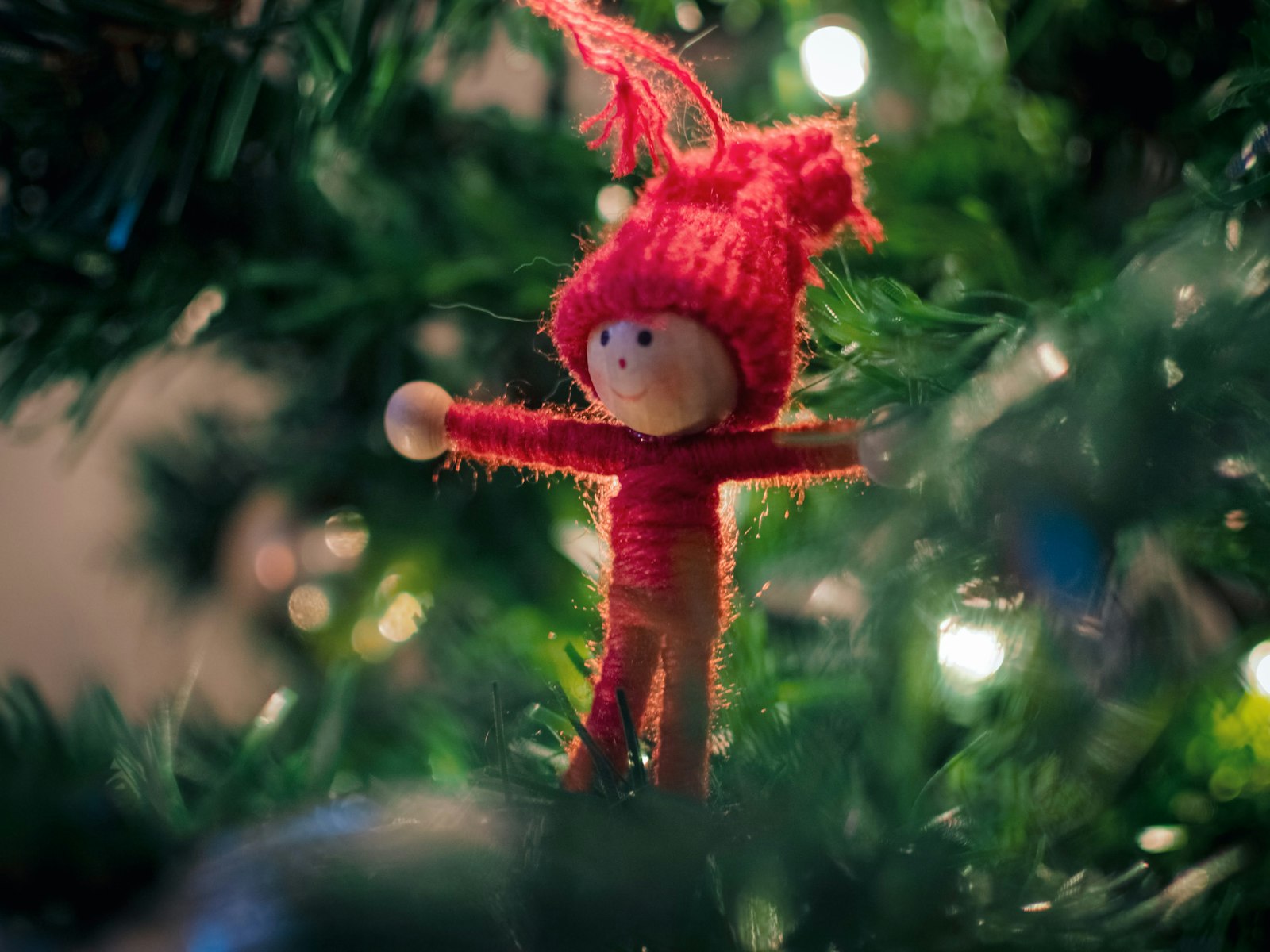 Soft red yarn doll ornament on a Christmas tree, a shatterproof kid-friendly choice