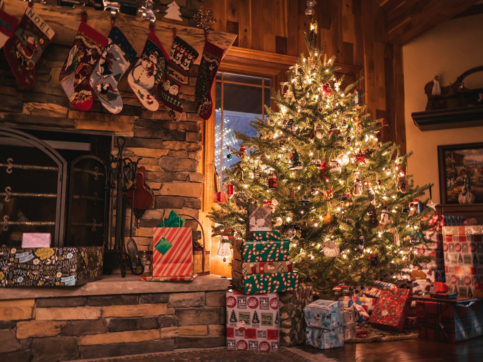 Christmas tree and wrapped presents beside a stone fireplace