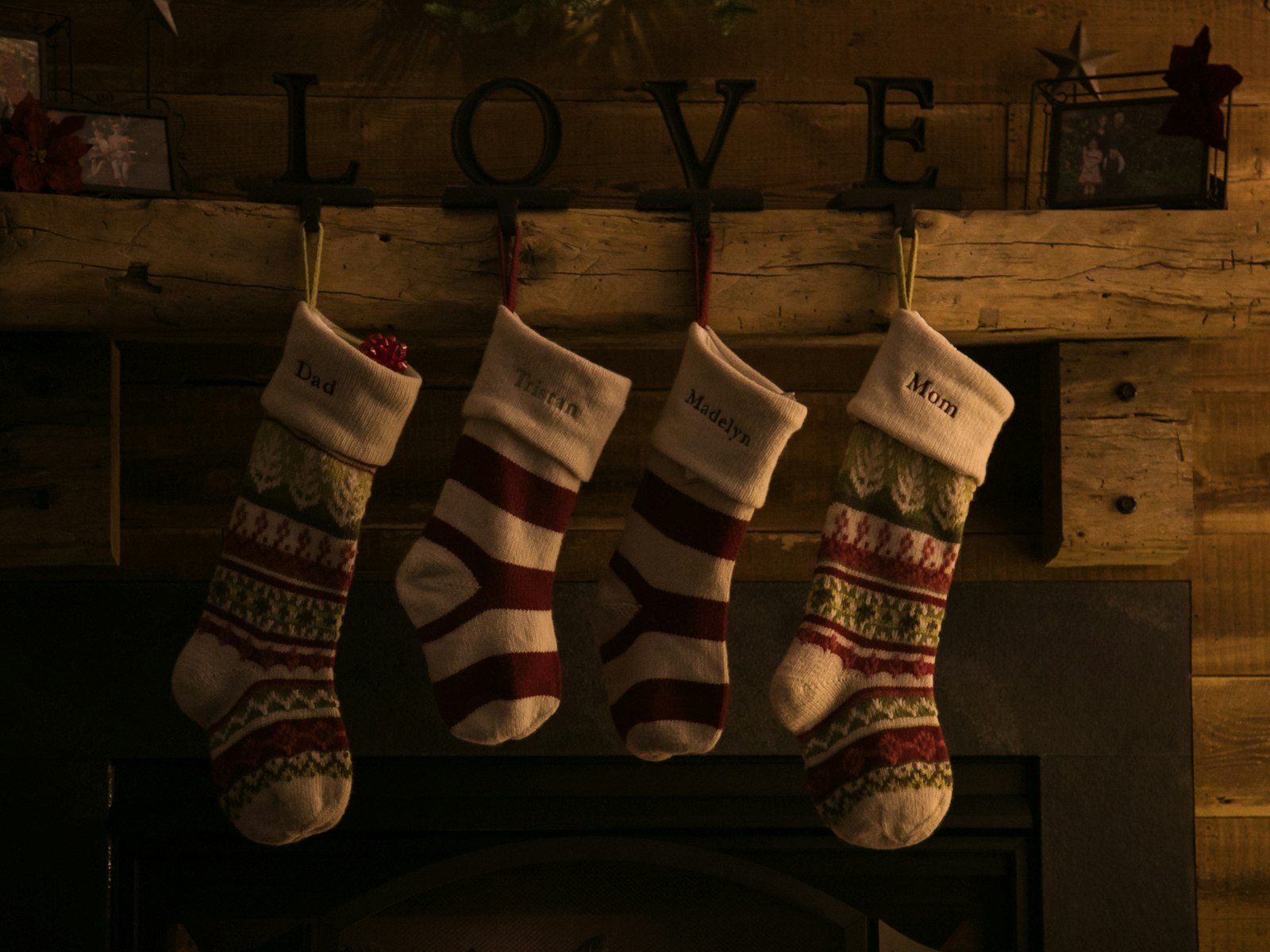 Four knit Christmas stockings hung evenly from a rustic wood mantel
