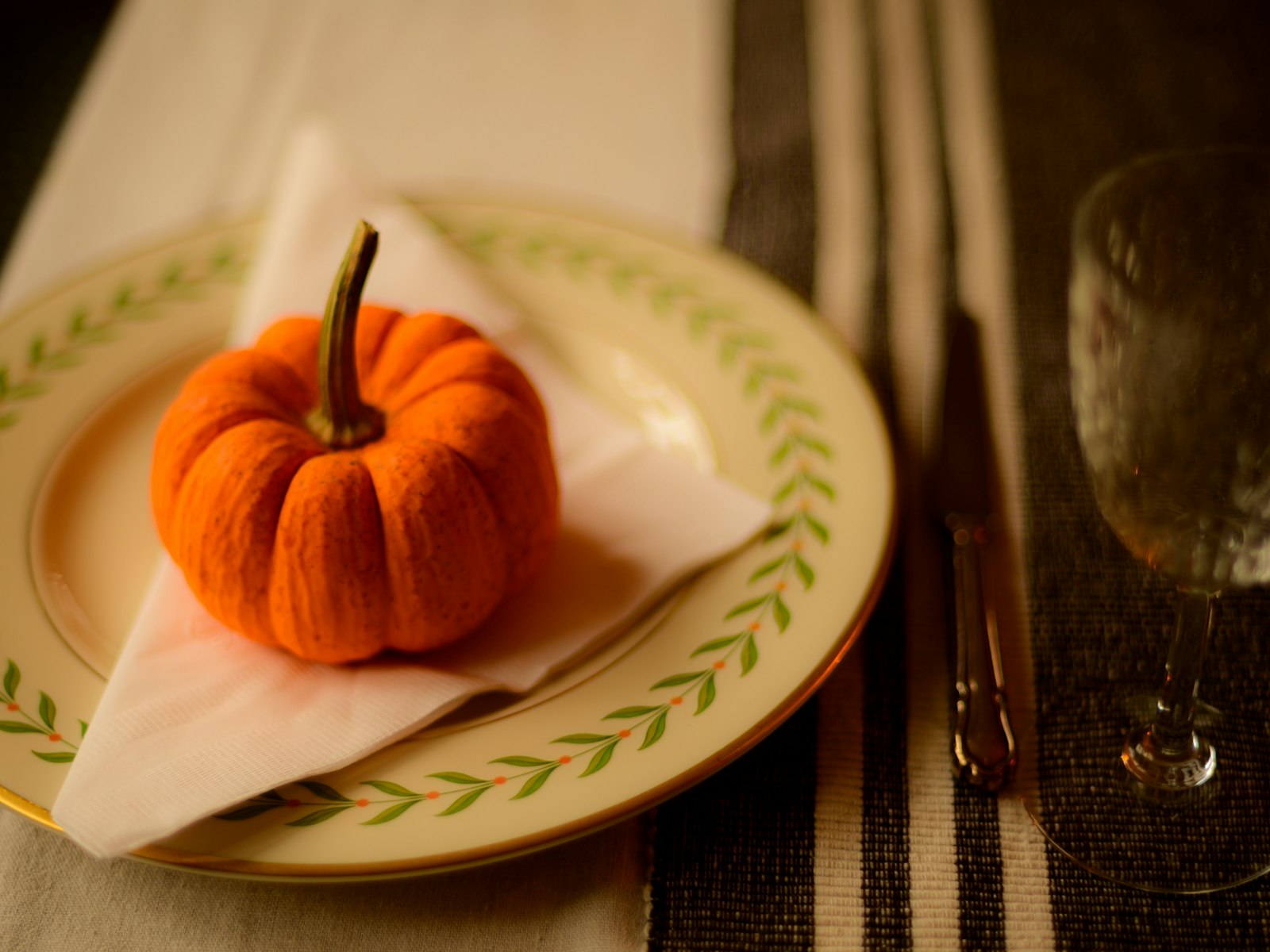 Mini pumpkin resting on a white napkin as a simple Thanksgiving place card