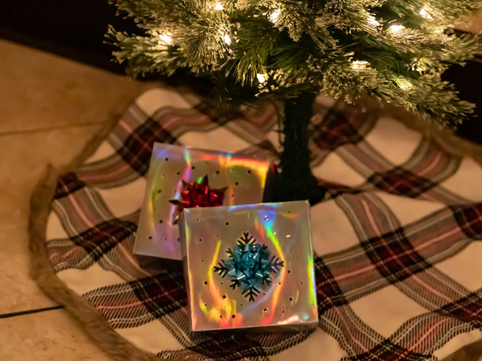 Plaid Christmas tree skirt with wrapped gifts under a flocked tree