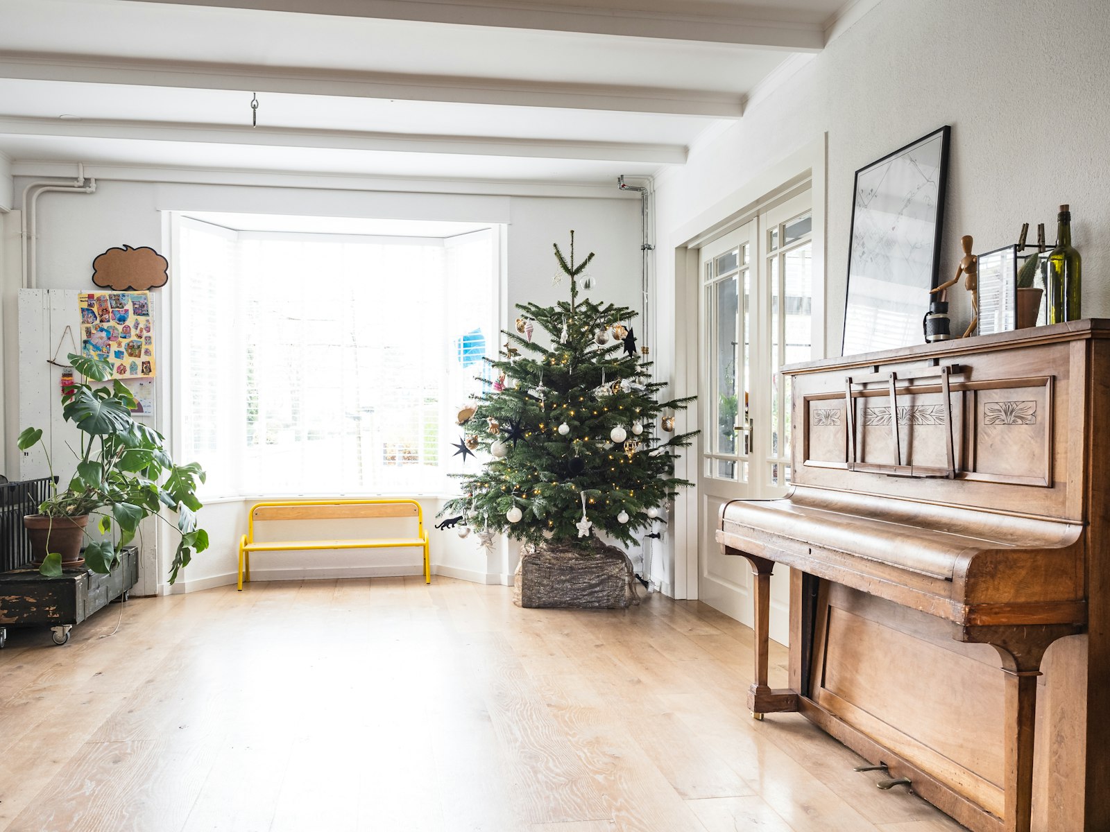Simple Scandinavian Christmas tree in a basket in a bright room with wood floors and a piano
