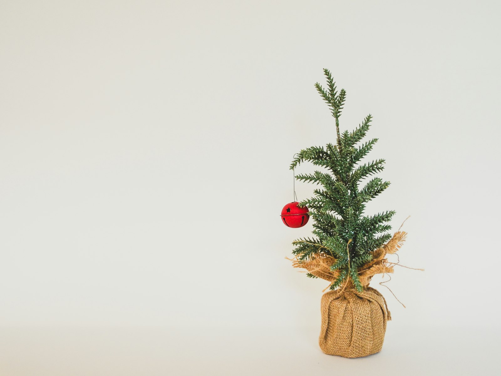 Small tabletop Christmas tree in a burlap wrap with a single red ornament