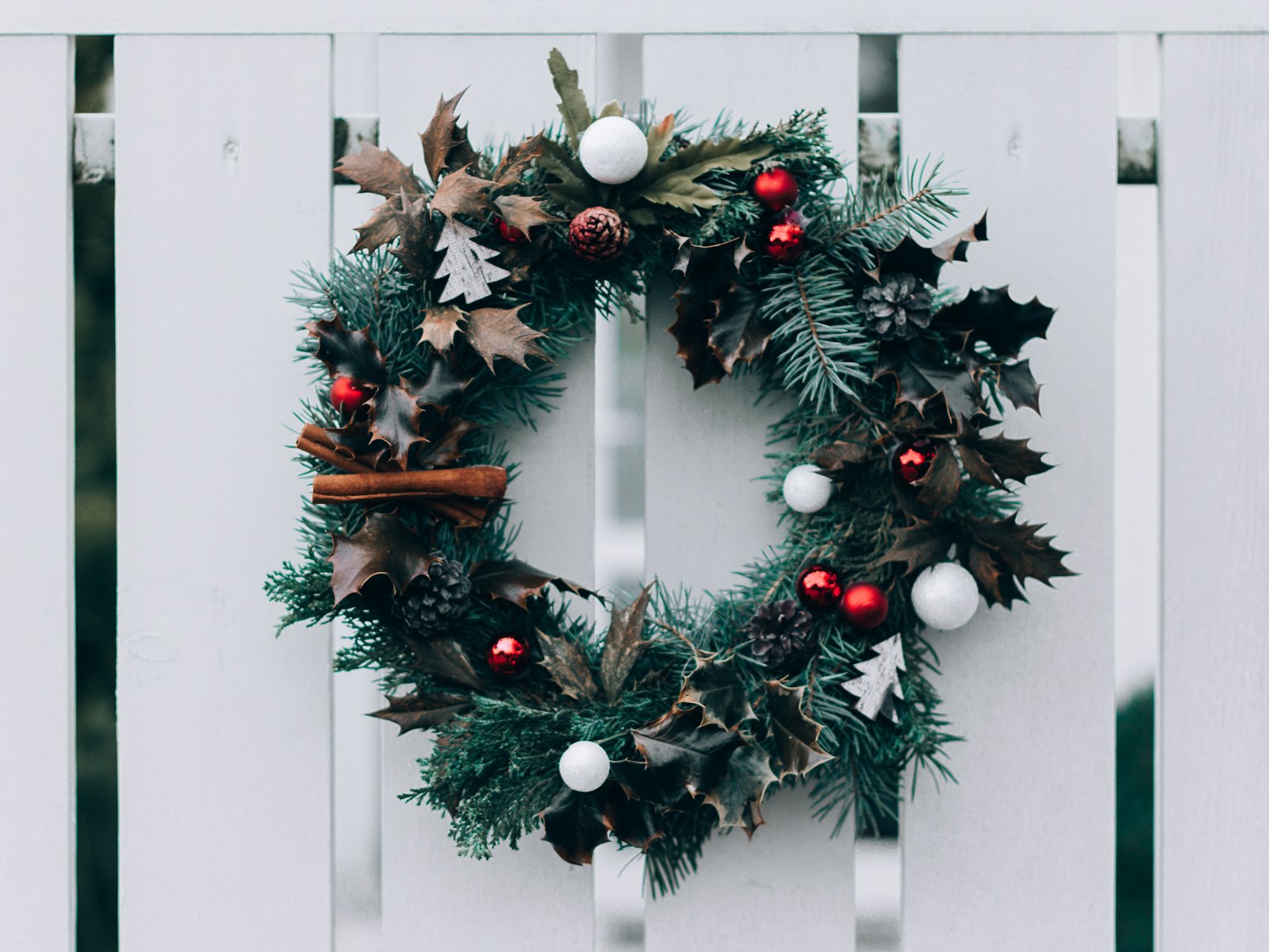 Natural Christmas wreath with white ornaments on a white door