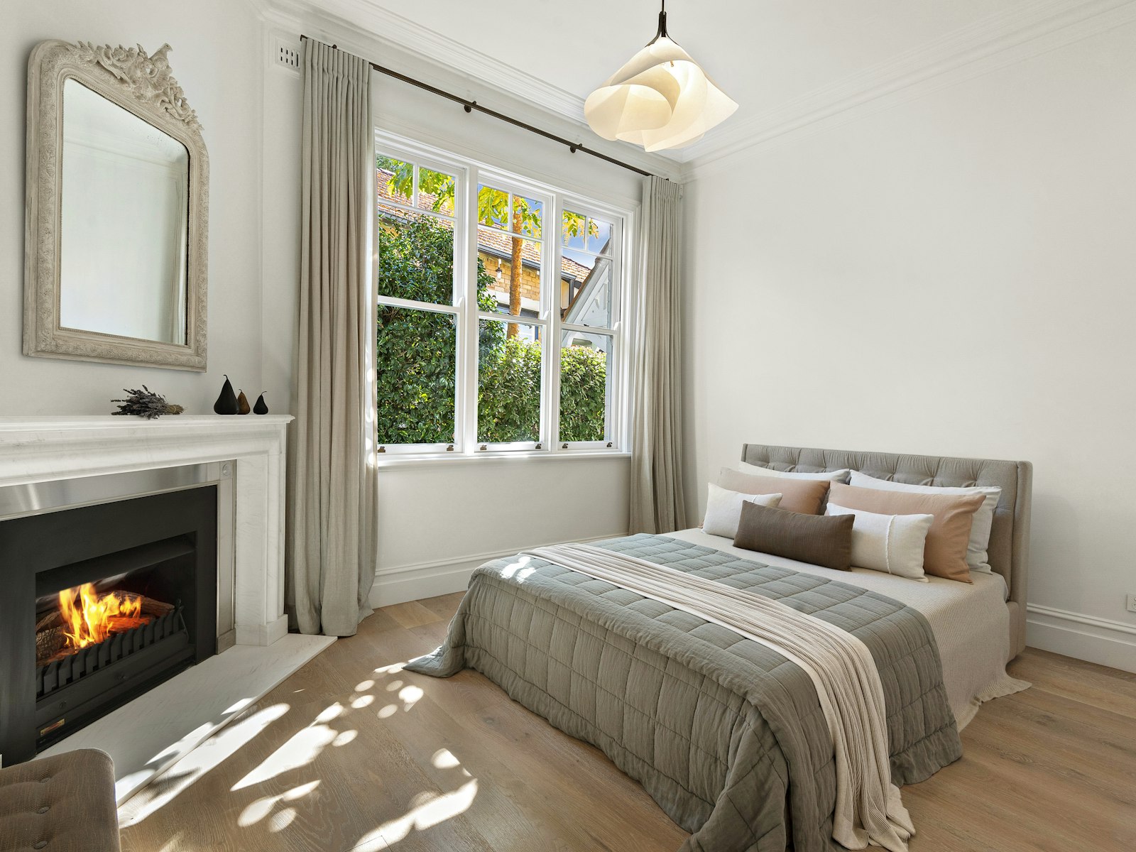 Winter bedroom with a fireplace, layered bedding and a wreath in the window