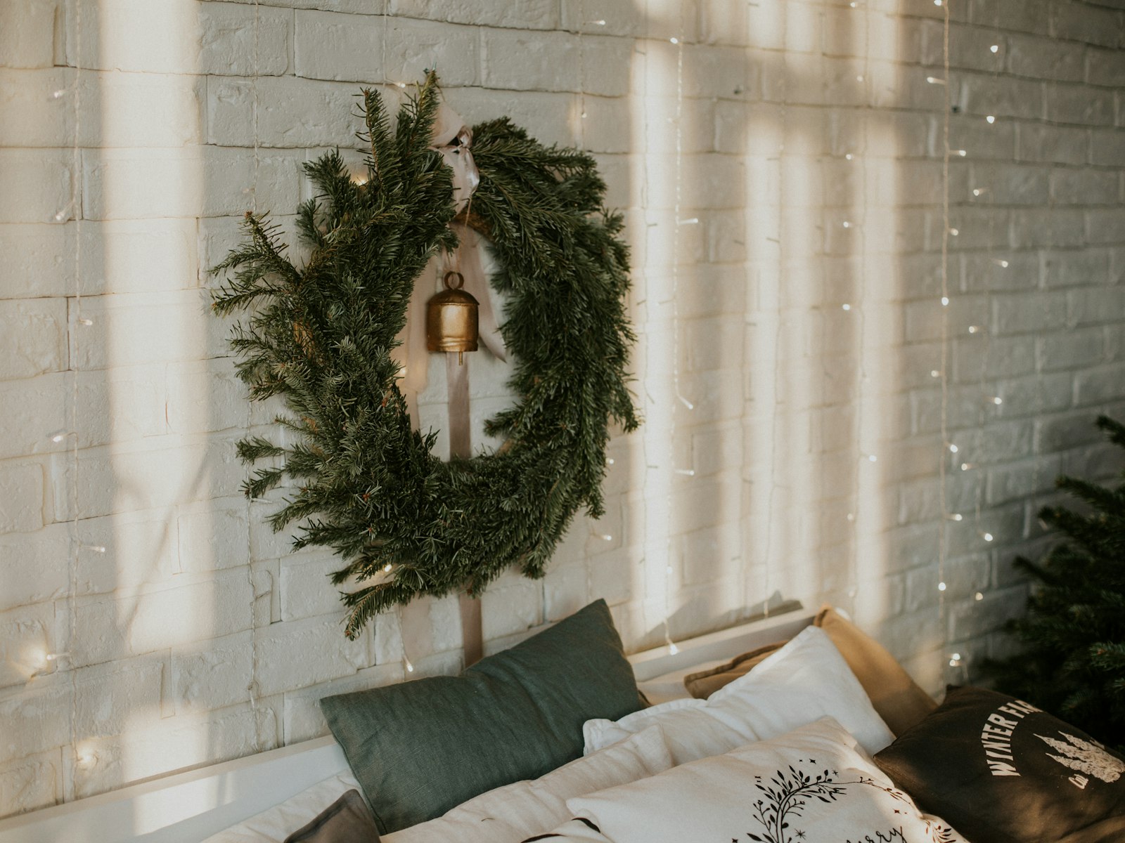Fresh wreath hung above a bed against a white brick wall